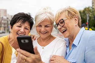 3 Frauen schauen gemeinsam auf ein Handy